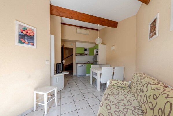 A compact living space with a kitchenette, a dining area, and a sofa.