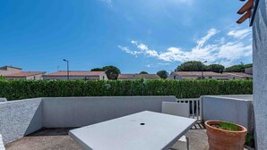 A rooftop terrace with a table and chairs, a potted plant, and a view of residential buildings. - Les jardins de Neptune, pool and relaxation (Saint-Cyprien)