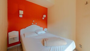 A single bed with a white headboard and footboard, two bedside tables, and a wall-mounted light fixture. - Les jardins de Neptune, pool and relaxation (Saint-Cyprien)