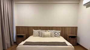 Ein Schlafzimmer mit einem großen Bett, einem Holz-Kopfstück, zwei Nachttischen und einem Fenster mit Vorhängen.