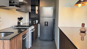 Eine moderne Küche mit Einbauofen, Edelstahlkühlschrank und einer Pendelleuchte.