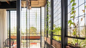 Een modern balkon met glazen hekwerk, potplanten en uitzicht op de stadsgezicht.