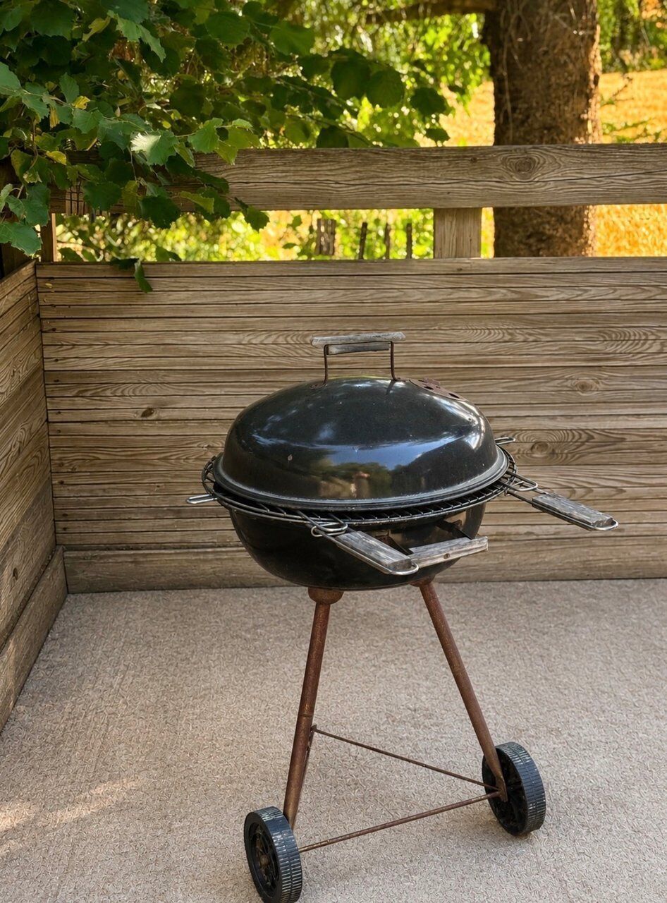 Un barbecue portatif sur roulettes, posé sur une surface en béton.