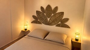 A bedroom with a bed, two bedside lamps, and a wall-mounted decorative leaf pattern. - Les noisetiers du Neyrial, quiet and countryside (Yssingeaux)
