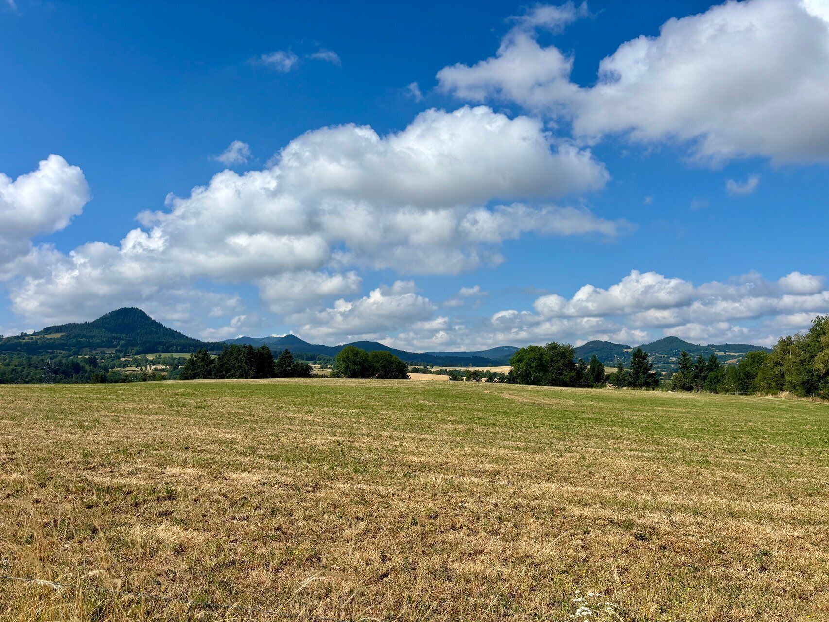 A wide-open field with distant mountains under a partly cloudy sky.
