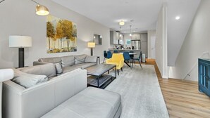 Ein modernes Wohnzimmer mit einer Couch, einem Couchtisch und einem Essbereich mit Stühlen.