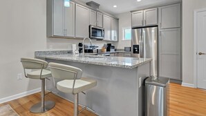 Eine moderne Küche mit einer Granit-Arbeitsplatte, Edelstahlgeräten und einer Theke mit Barhocker.