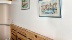 Ein Zimmer mit einem hölzernen Kopfende, zwei gerahmten Kunstwerken mit Küstenmotiven und einer weißen Decke.
