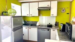 Eine kompakte Küche mit Kühlschrank, Geschirrspüler und Kaffeemaschine.
