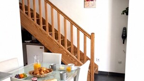 Ein Essbereich mit einem für das Frühstück gedeckten Tisch, einer Treppe und einem an der Wand befestigten Fön.