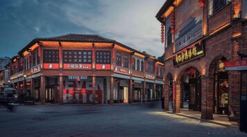Un edificio tradicional con varias fachadas comerciales, incluyendo un llamativo rótulo que dice 'SEVEN BUS'.