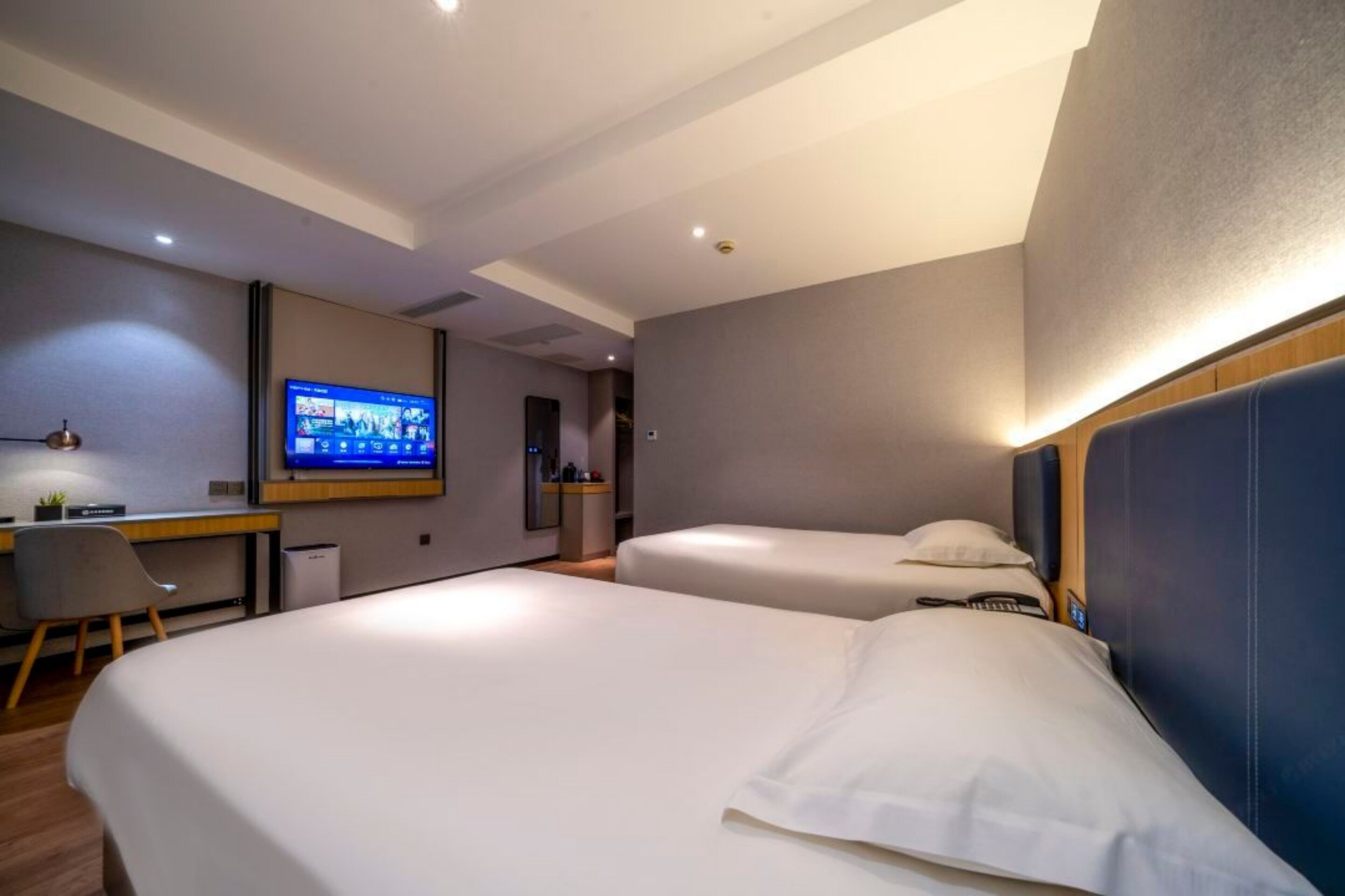 Une chambre d’hôtel comprenant un lit, un bureau, une chaise, une télévision et une petite table.