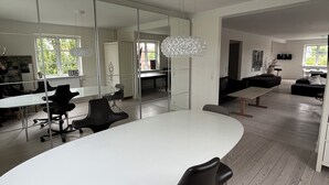 Un intérieur moderne avec une grande table blanche, des chaises de bureau noires et un lustre en cristal unique.