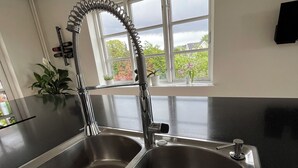Une cuisine dotée de deux éviers en acier inoxydable, d’un robinet moderne et d’une fenêtre donnant sur un paysage verdoyant.