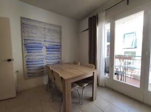 Ein Zimmer mit einem Holzespeisetisch, Stühlen, einem großen abstrakten Gemälde und einer Schiebetür aus Glas, die zu einem Außenbereich führt.
