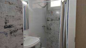 Un baño con ducha, lavamanos e inodoro.