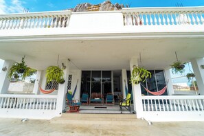 A white building with a covered porch, potted plants, and outdoor furniture. - Flor de Lis Beach House (Playas)