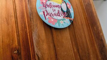 Una porta in legno con un cartello circolare che riporta la scritta 'Welcome to Paradise'.