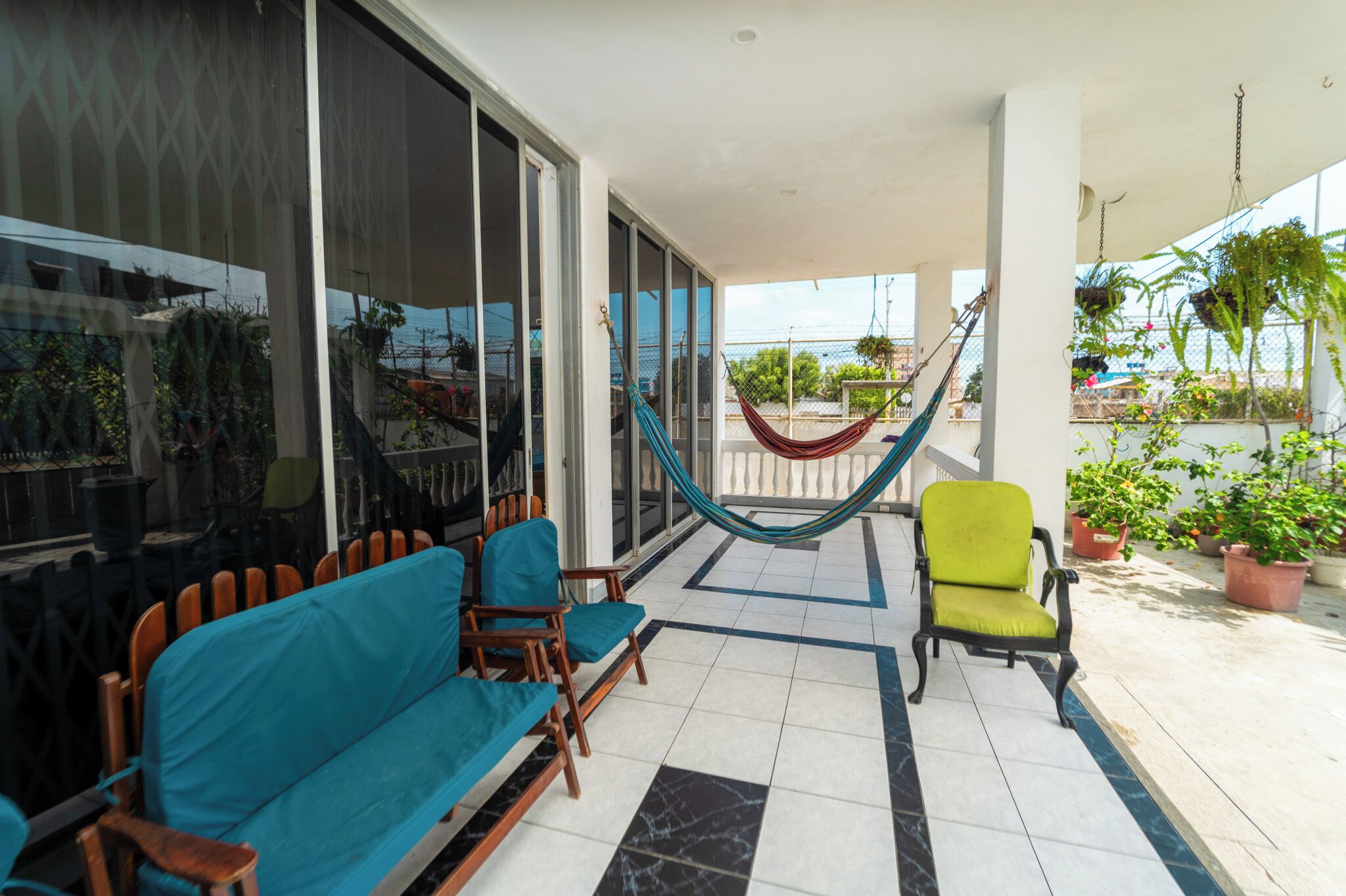 A balcony with a hammock, chairs, and potted plants.