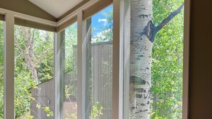 A room with a large window, a wooden floor, a dark-colored sofa, and a small table. -  3bd-2ba stand alone condo with POOL and no hwy noise 5 min- Vail Village (Vail)