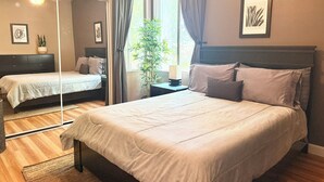 A bedroom with a large bed, a bedside table, a mirror, and a window with curtains. - Home-like 3-bedroom condo with Resort Amenities in beautiful Phoenix (Phoenix)