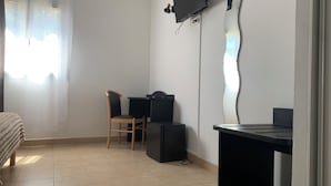 A room with a bed, a desk, a chair, a TV, and a mirror. - Le Clos du Thoronet (Le Thoronet)