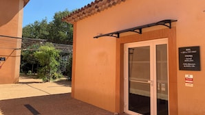 A hotel entrance with a tiled roof, a glass door, and a sign indicating room availability. - Le Clos du Thoronet (Le Thoronet)