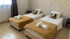 A hotel room with two beds, each with a brown bedspread and white linens, a textured wall, and a small bedside table with a lamp. - Le Clos du Thoronet (Le Thoronet)