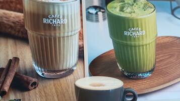 Un panneau affichant le menu avec deux options de boissons, une tasse de café et une table en bois.