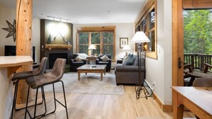 Un salon chaleureux avec une cheminée, des meubles en bois et une vue sur l’extérieur.