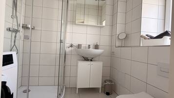 A modern bathroom with a glass shower enclosure, a white sink, and a toilet.