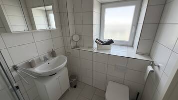 Un baño moderno con lavamanos, espejo, inodoro y ventana.