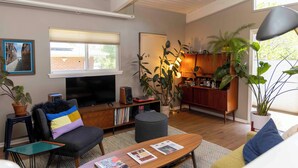 Ein Wohnzimmer mit Fernseher, Büchern, einem Couchtisch und einer Couch.