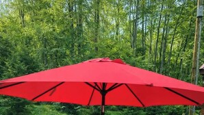 A picnic table with a red umbrella in a grassy outdoor area. - Rustic Tiny Cabin retreat with AC (Union Mills)