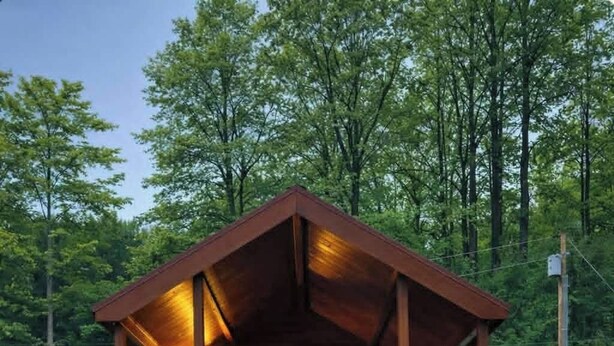 A wooden cabin with a porch, a railing, and a wreath. - Rustic Tiny Cabin retreat with AC (Union Mills)