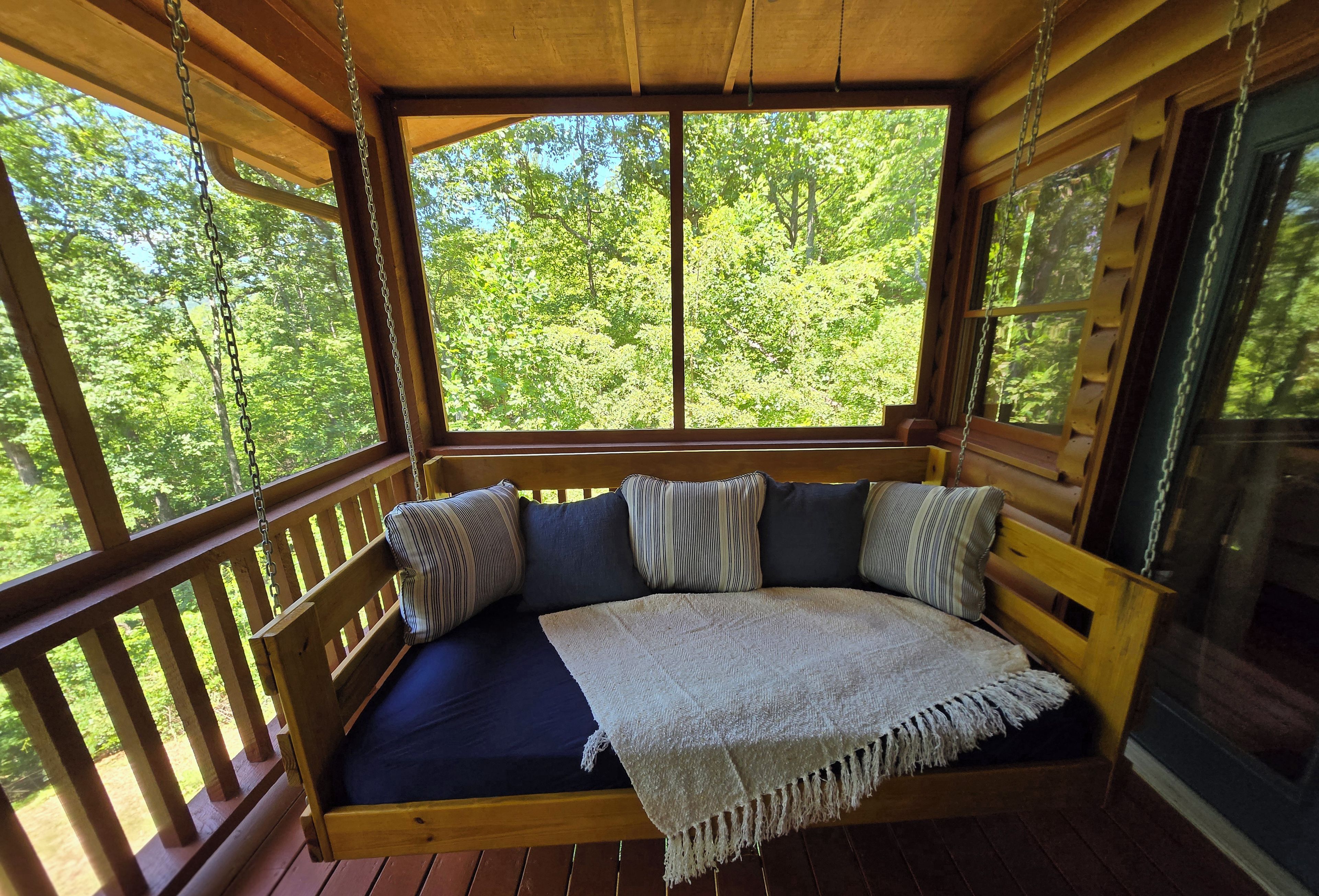 A wooden deck with a built-in bench featuring cushions and a throw blanket.