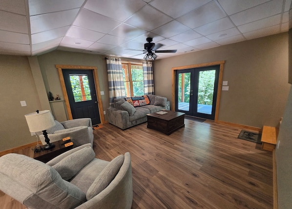 A living room with a sectional sofa, a coffee table, and a ceiling fan. - Hideaway Hollow Cabin, Mtn view, Bed swing, hot tub near Ocoee River/Copperhi... (Murphy)