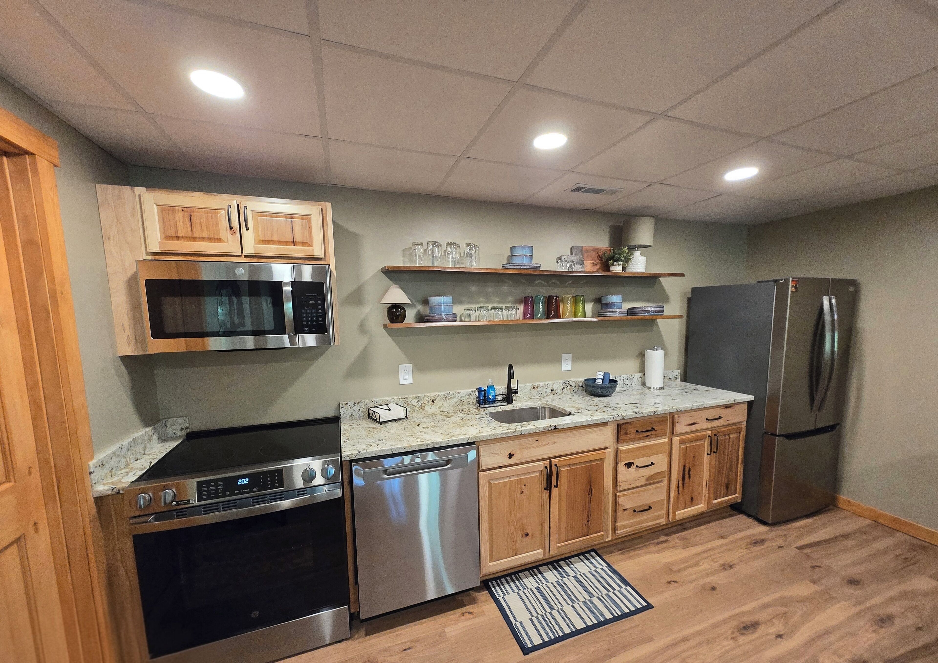 A modern kitchen with stainless steel appliances, wooden cabinets, and a marble countertop.