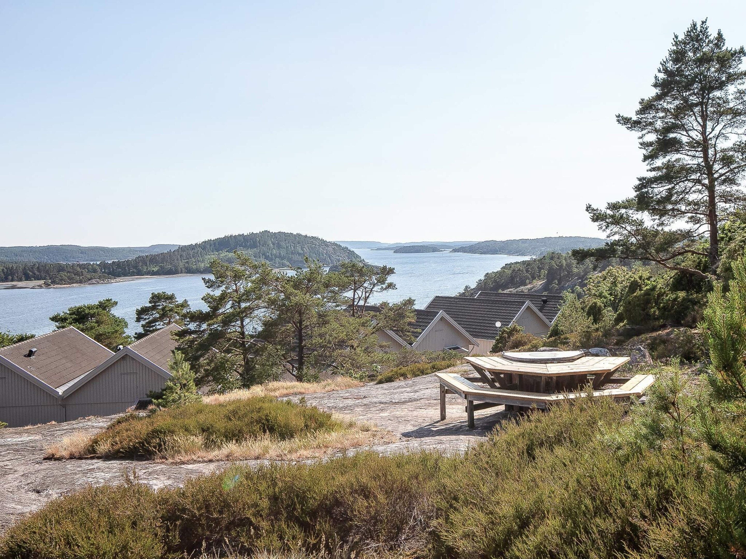 Une propriété située sur la côte, comprenant plusieurs chalets, une terrasse en bois et offrant une vue sur la mer et les îles lointaines.