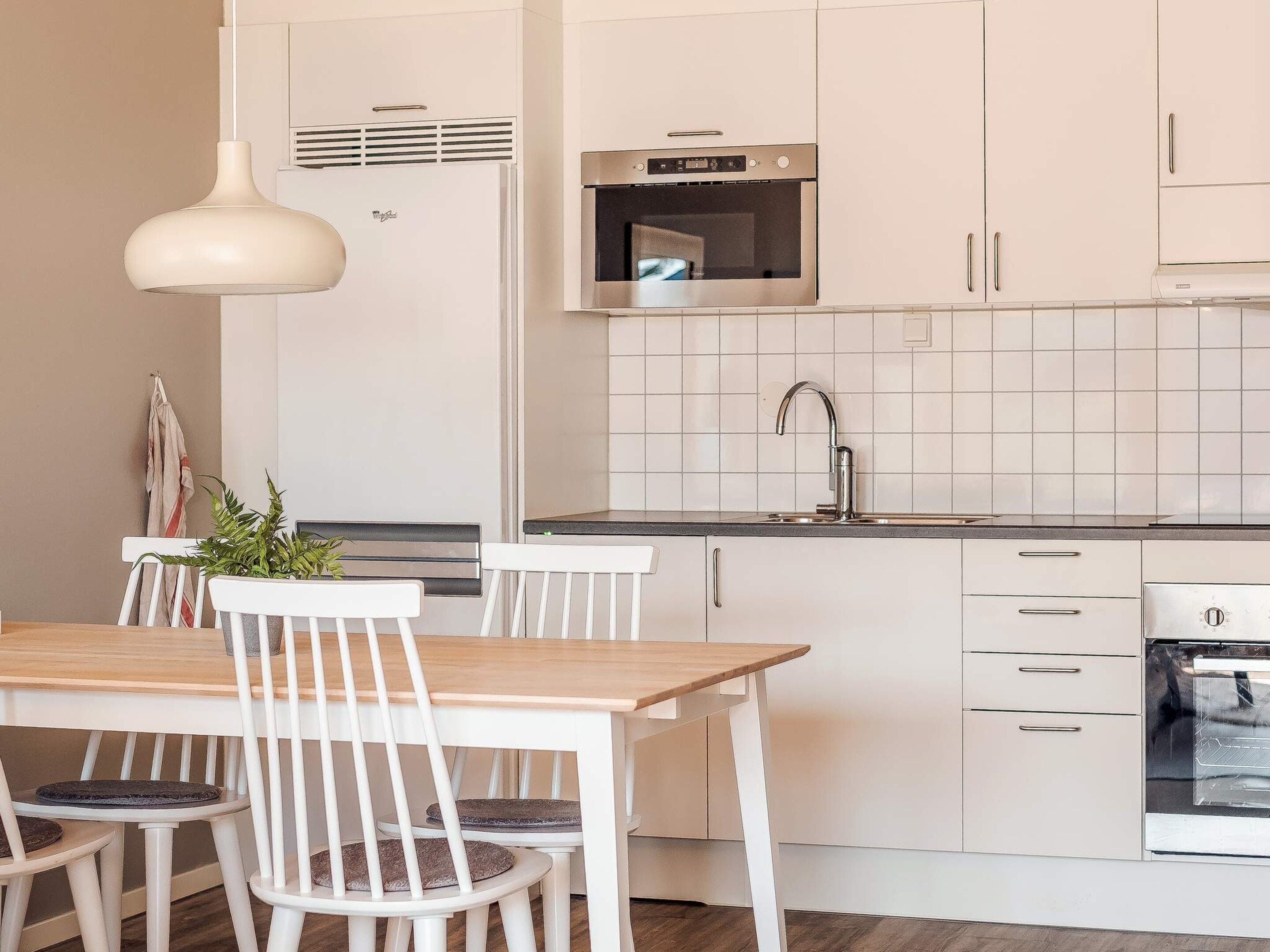 A modern kitchen with white cabinetry, a built-in oven, and a stainless steel range hood.
