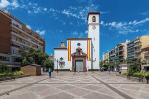 A church with a bell tower, a plaza with benches, and surrounding buildings. - LXR Navegante 2-Bedroom Next to the Sea (Fuengirola)