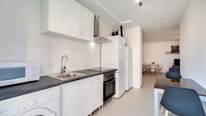 Moderni keittiö, jossa on mikroaaltouuni, uuni ja pesuallas.