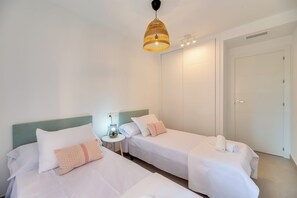 A hotel room with two single beds, a bedside table with a lamp, a wardrobe, and a hanging light fixture. - LXR Navegante 2-Bedroom Next to the Sea (Fuengirola)