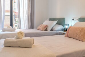 Habitación de hotel con dos camas, una mesita de noche y una ventana con cortinas.
