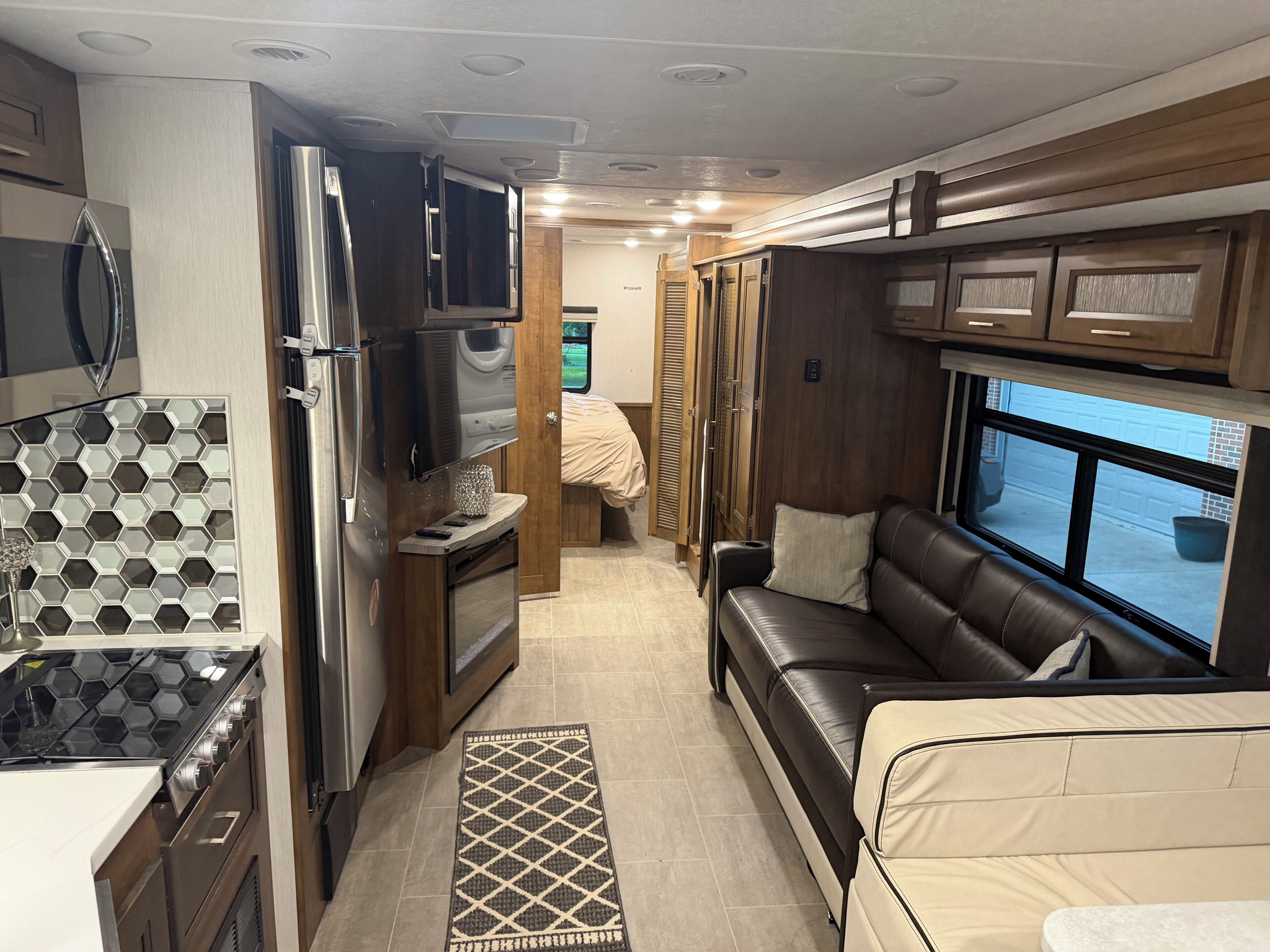 Een compact RV-interieur met een kitchenette, een bank en een raam met uitzicht.