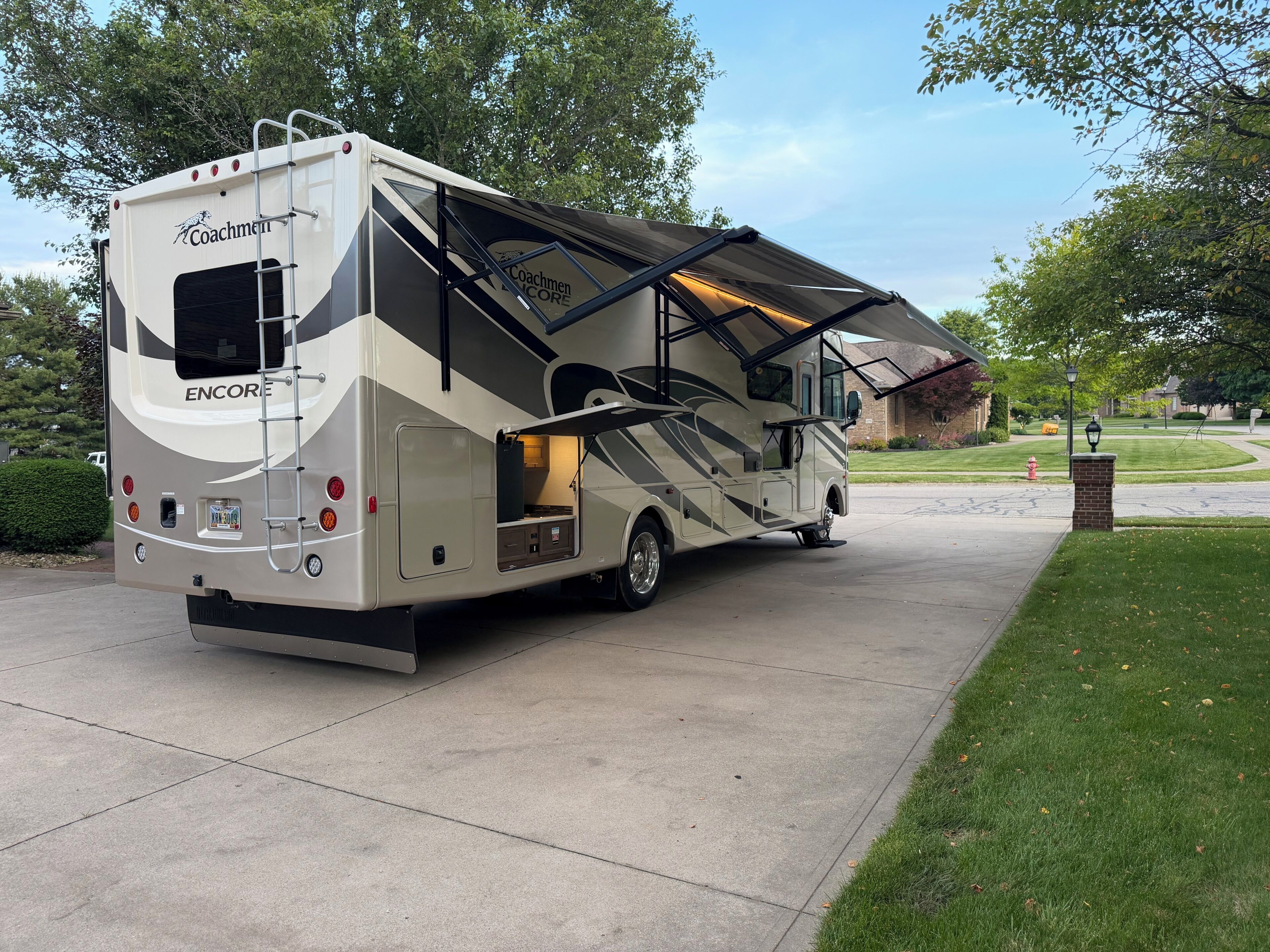 Een Coachman Encore RV staat op een oprit, met een afgedekt achtergedeelte en een zichtbare keukenruimte.