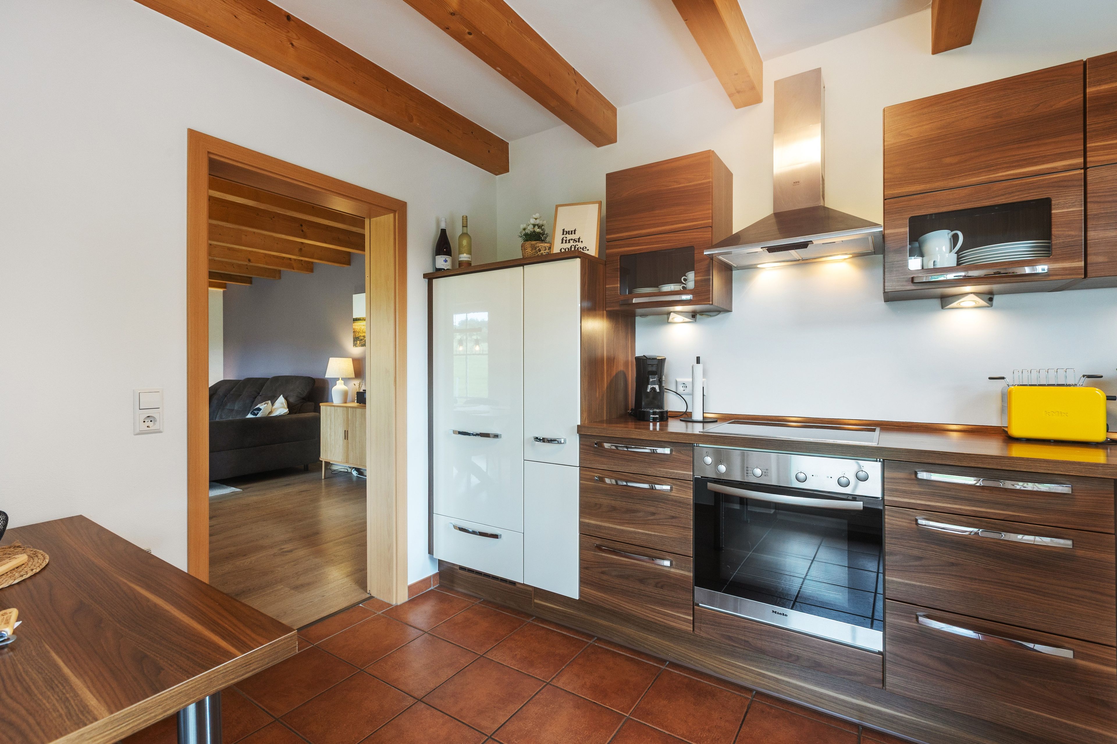 A modern kitchen with wooden cabinets, a built-in oven, and a yellow toaster.