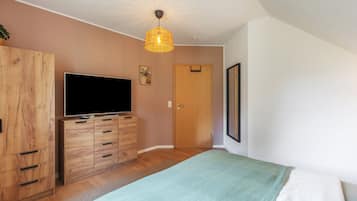 Ein Schlafzimmer mit einem Bett, einem Holzschrank, einem Fernseher und einer Tür.