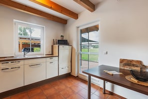 Eine Küche mit weißen Schränken, einer Holz Arbeitsplatte, einem eingebauten Backofen und einem Fenster mit Blick auf einen Garten.