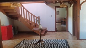 A staircase with wooden railings, a red cabinet, a patterned rug, and a table with a vase.